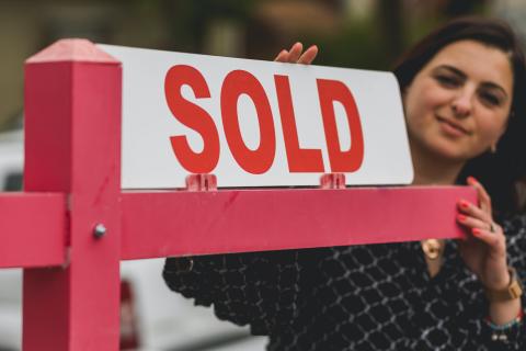 Person putting sold sign up in front of house