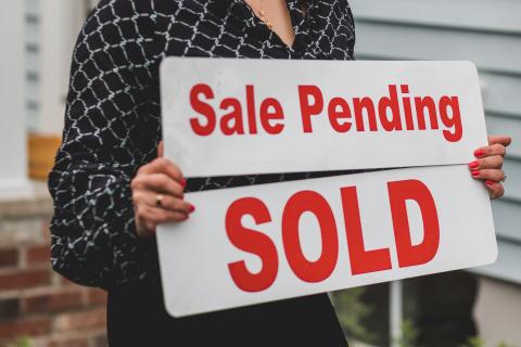Person holding a sale pending sign