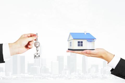 Hands holding a model house and a key with a house keychain